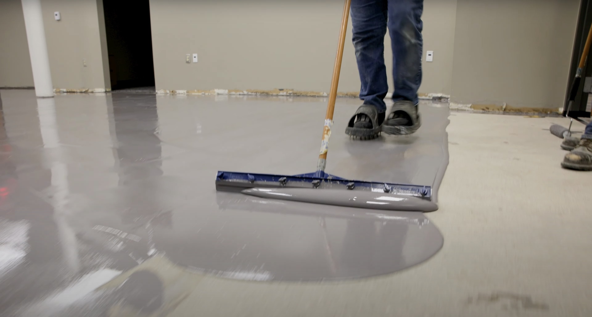 Professional concrete floor finishing work with specialized squeegee tool